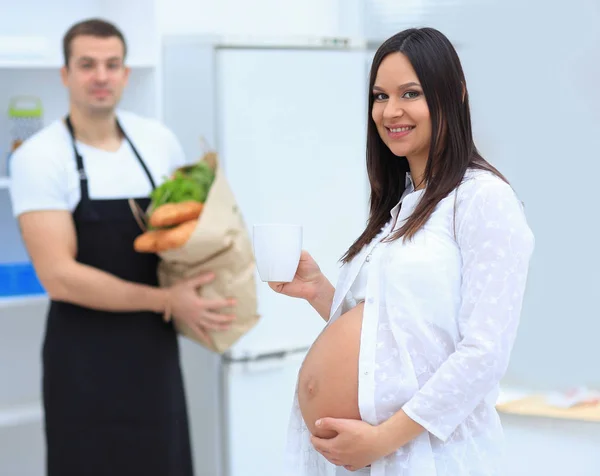 Glada gravida par vegetarianer i köket. — Stockfoto