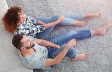 yeni bir oturma odasında bir halı üzerinde oturan yeni evli çift