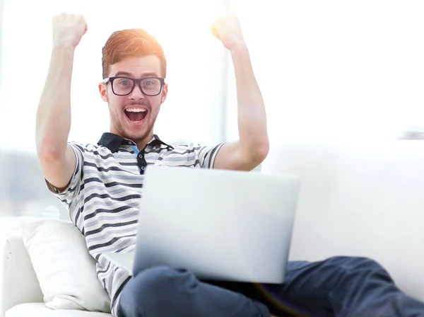 Щасливий чоловік з ноутбуком сидить на дивані — стокове фото