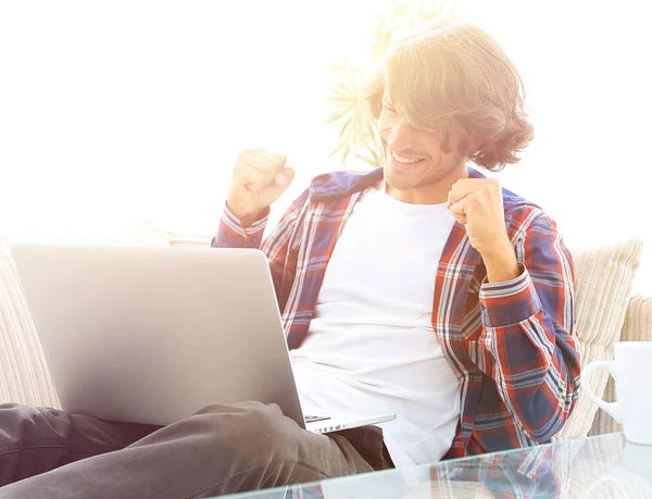 Tipo feliz con portátil sentado en el sofá. concepto de éxito — Foto de Stock