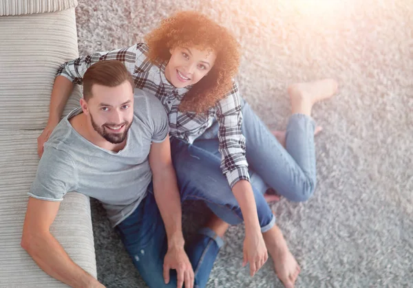 Unga paret sitter på mattan i det nya vardagsrummet — Stockfoto