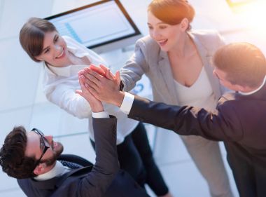 Başarılı bir iş ekibi ofiste birbirlerine beşlik çakıyor.