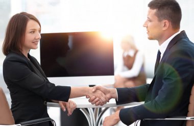 Pazarlık masasında el sıkışan iş ortakları.