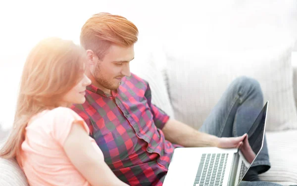 Dizüstü bilgisayarlı genç adam ve kız kanepede oturuyor. — Stok fotoğraf