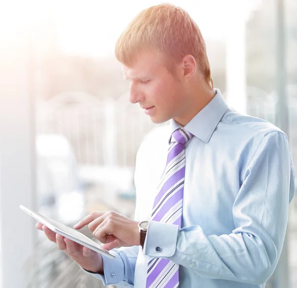 Beau jeune homme en chemise bleue à l'aide d'une tablette — Photo