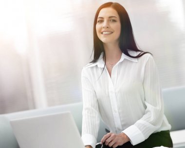 bulanık bir arka plan üzerinde bir masada oturan başarılı genç kadın.