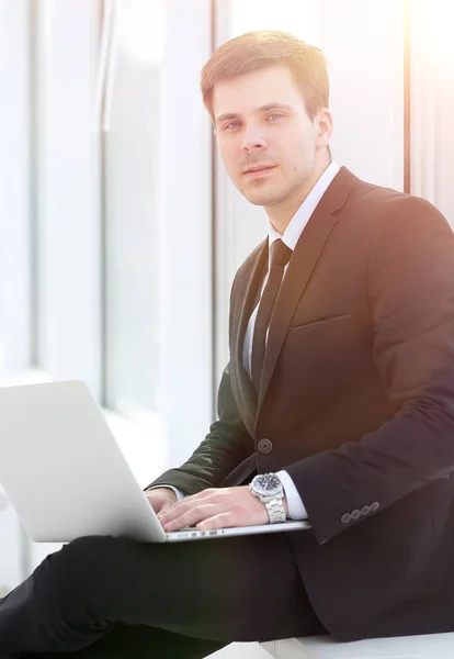 Jeune professionnel avec ordinateur portable sur fond de fenêtre de bureau — Photo