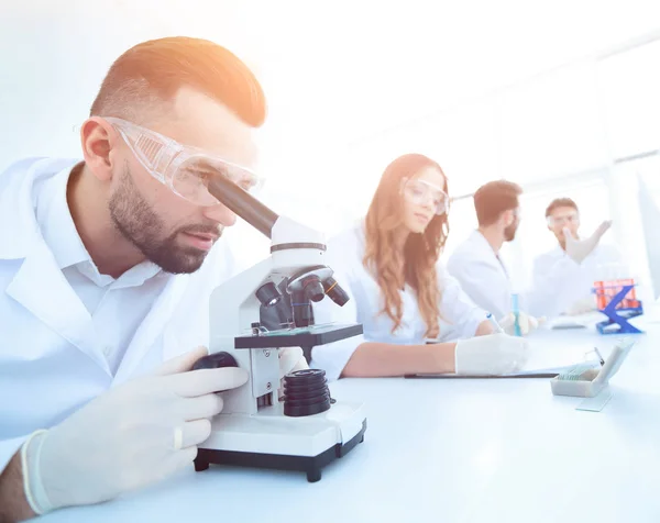 Mężczyzna laborantki patrząc na próbki w mikroskopie — Zdjęcie stockowe