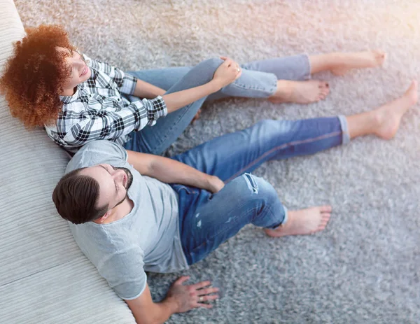 Couple nouvellement marié assis sur un tapis dans un nouveau salon — Photo