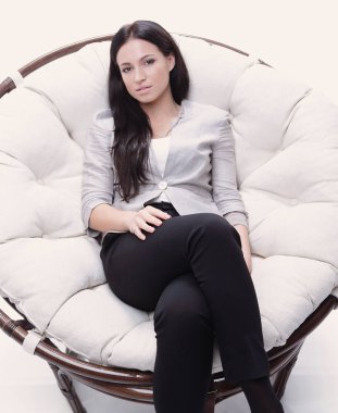 Yuvarlak, yumuşak bir sandalyede oturan modern genç kadın.