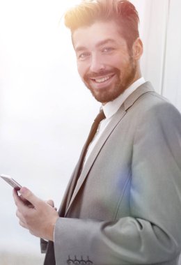 Takım elbiseli şık adam telefonla bilgi okuyor.