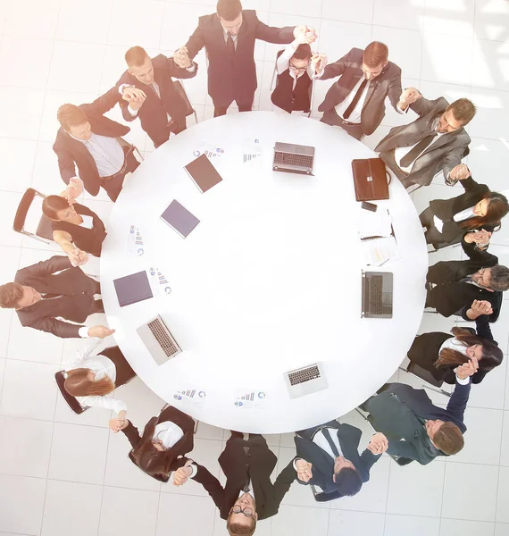 Duże firmy zespół siedzi przy okrągłym stole i podnoszenie jego h — Zdjęcie stockowe