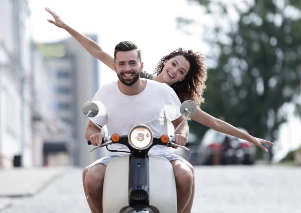 Gelukkige jonge paar rijden een scooter in de stad op een zonnige dag — Stockfoto