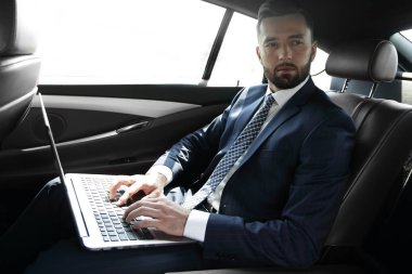 İş adamı arabaya otururken dizüstü bilgisayar ile çalışma