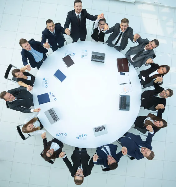 Groot business team zitten aan de ronde tafel en zijn handen omhoog — Stockfoto