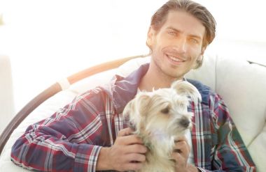 gülümseyen bir adam büyük bir koltukta otururken köpeğini okşayarak Close-Up.