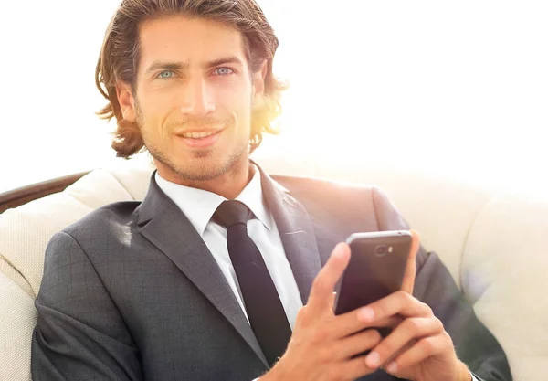successful business man with a smartphone sitting in a comfortable chair
