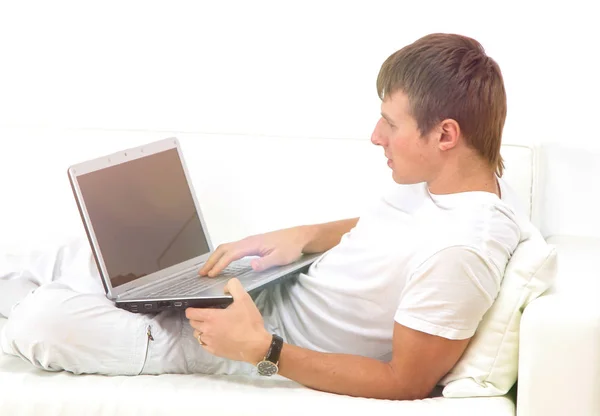Jovem muito focado usando laptop enquanto sentado confortavelmente . — Fotografia de Stock
