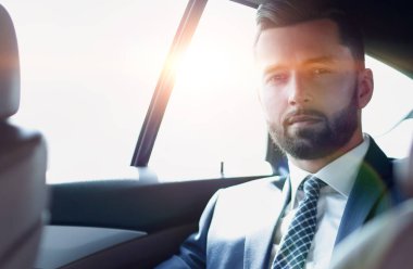 arabanın arka koltuğunda oturan yakışıklı sakallı işadamı