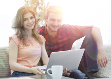 Genç çift çalisarak koltukta oturan laptop