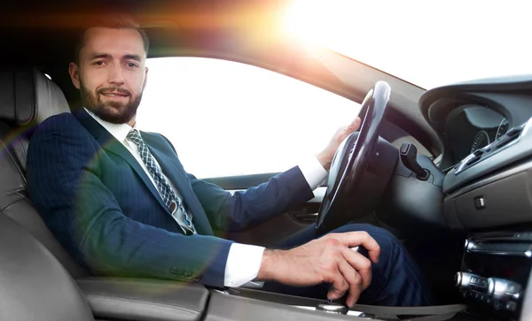 View from the side confident businessman sits at the wheel of a car — Stock Photo, Image
