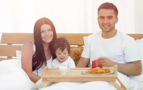 Familjen äter frukost i sängen hemma — Stockfoto