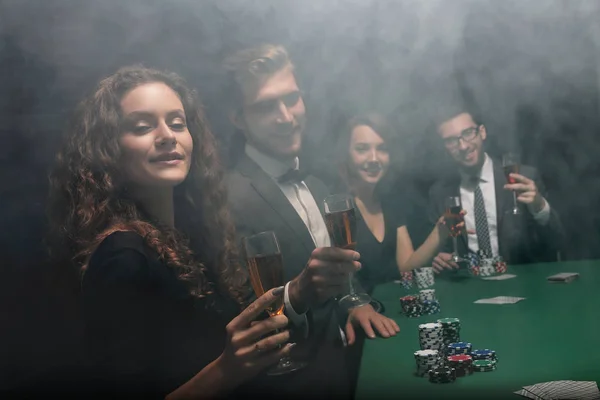 Groep vrienden zitten op de speeltafel in casino — Stockfoto