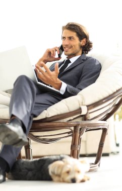 onun evinde sandalyede oturan smartphone cep telefonu ile konuşurken işadamı