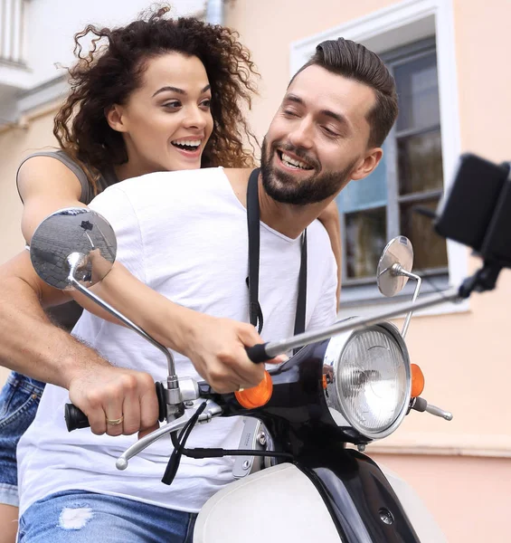 Счастливая пара на скутере делает селфи на смартфоне на улице — стоковое фото