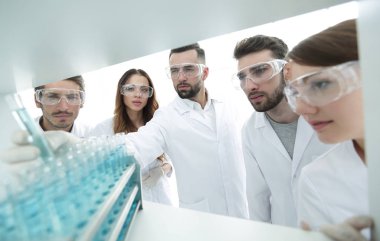 arka plan görüntüsü sıvı cam tüp içinde eğitim microbiologists oluşan bir gruptur.
