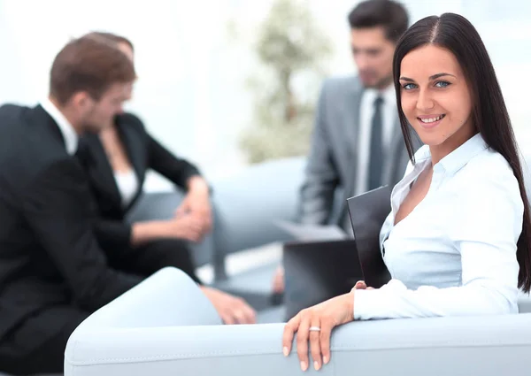Giovane donna d'affari seduta in ufficio in background business team — Foto Stock