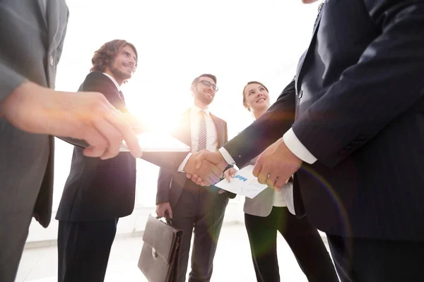 Os funcionários olham para os parceiros de negócios handshake — Fotografia de Stock