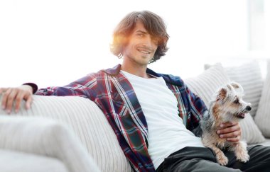 şık adam köpeğiyle kanepede oturan.