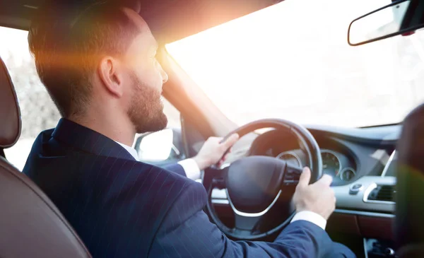 businessman sits at the wheel in his car and looks at the road