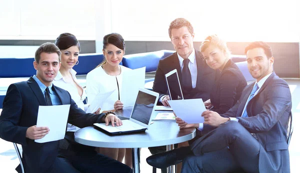 Gruppe von Geschäftsleuten mit Dokumenten sitzt an einem Tisch in der Lobby der Bank. — Stockfoto