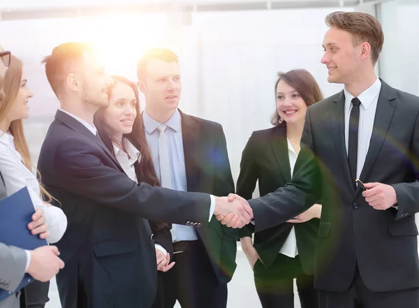 Equipe de negócios olha para os parceiros de negócios handshake — Fotografia de Stock