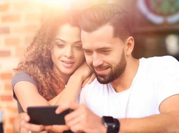 Lyckligt par använder en smartphone som sitter i terrass — Stockfoto