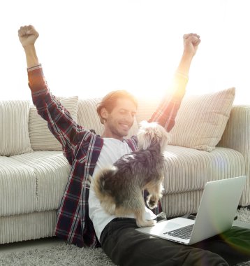 geniş bir oturma odasında otururken köpeğiyle mutlu adam