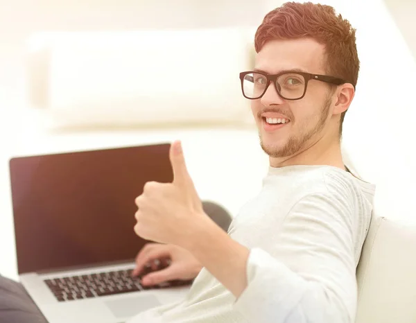 Modern young sitting in front of the open laptop and showing thumb up — Stock Photo, Image