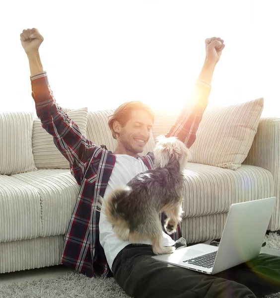 geniş bir oturma odasında otururken köpeğiyle mutlu adam