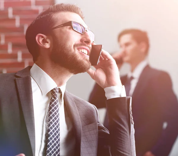 Handsome businessman speaking on mobile phone in office — Stock Photo, Image