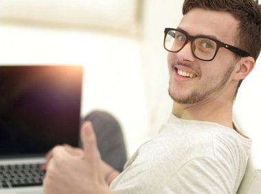 açık belgili tanımlık laptop önünde oturan ve gösterilen modern genç yukarı başparmak