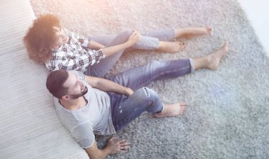 yeni bir oturma odasında bir halı üzerinde oturan yeni evli çift