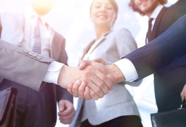 Equipe olhando para um parceiro handshake de negócios . — Fotografia de Stock