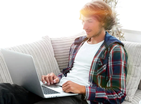 소파에 앉아 노트북에서 일 하는 젊은 남자 — 스톡 사진