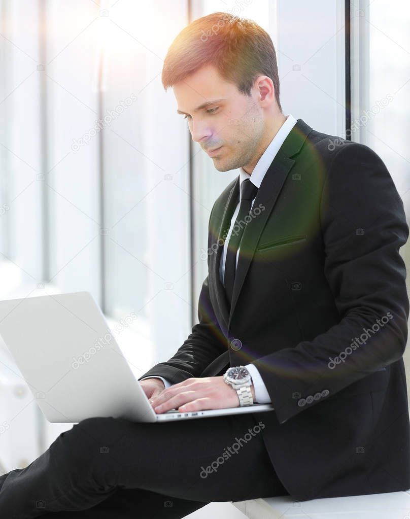 young professional with laptop on background of office window