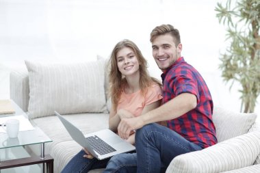 Dizüstü bilgisayarı olan iki öğrenci kanepede oturuyor.