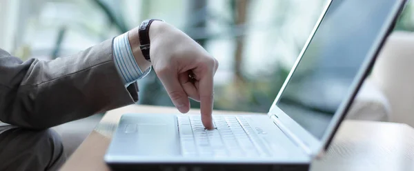 Aanraking van een vinger aan de laptop computertoetsenbord, zijaanzicht — Stockfoto