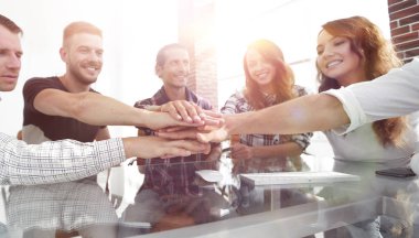 Yaratıcı iş ekibi ofiste el ele tutuşuyor.