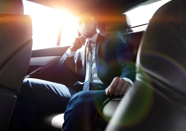 Empresário falando ao telefone enquanto sentado no banco de trás de seu carro — Fotografia de Stock